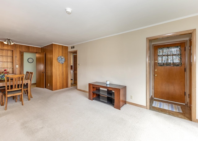 dining area with ornamental molding, wood walls, baseboards, and carpet floors