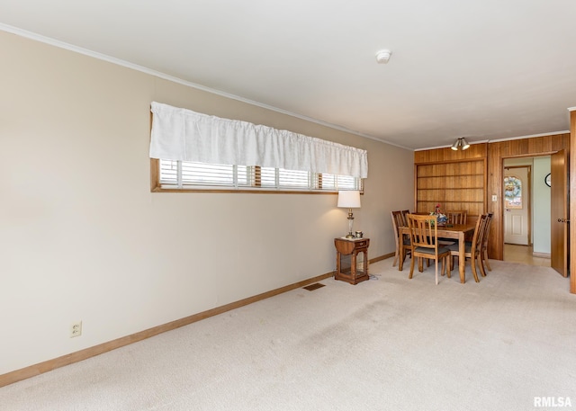 dining area featuring baseboards, crown molding, carpet, and wood walls