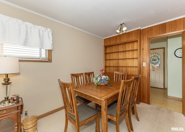 dining space featuring crown molding, baseboards, built in features, and light carpet
