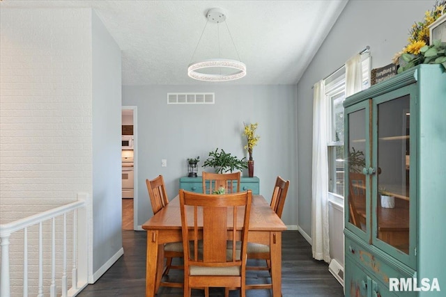 dining space with a chandelier, dark wood finished floors, baseboards, and baseboard heating