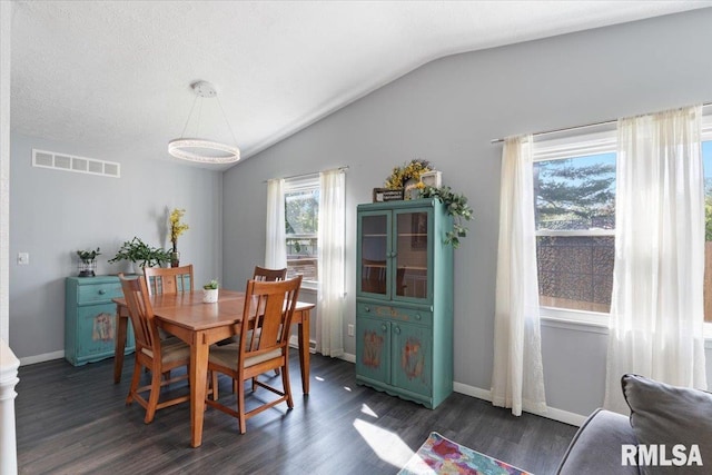 dining room featuring dark wood-type flooring, vaulted ceiling, and baseboards