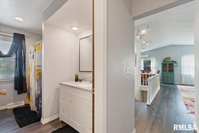 bathroom with wood finished floors, lofted ceiling, vanity, and baseboards