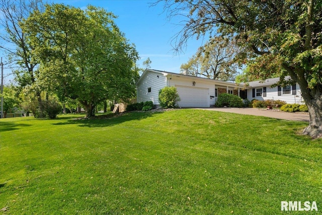 view of green lawn featuring a garage and driveway