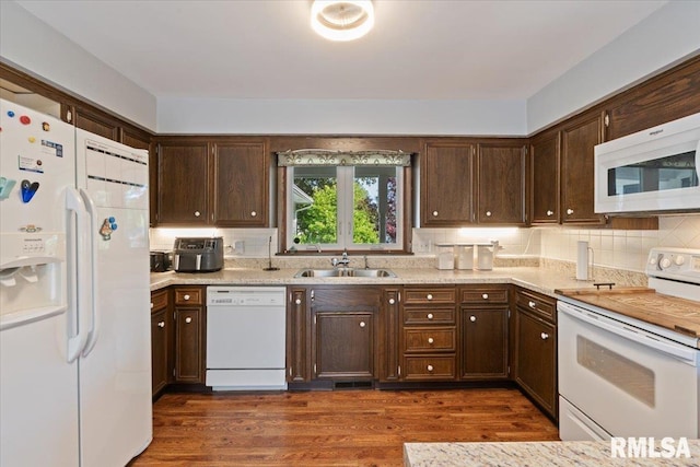 kitchen featuring white appliances, a sink, light countertops, and dark wood-style floors