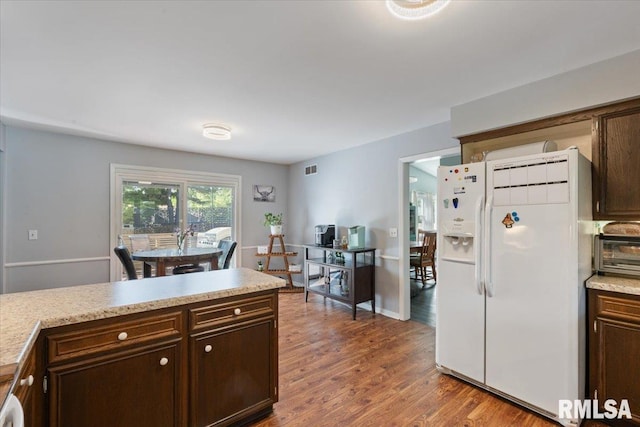 kitchen featuring white fridge with ice dispenser, light countertops, dark brown cabinets, and wood finished floors