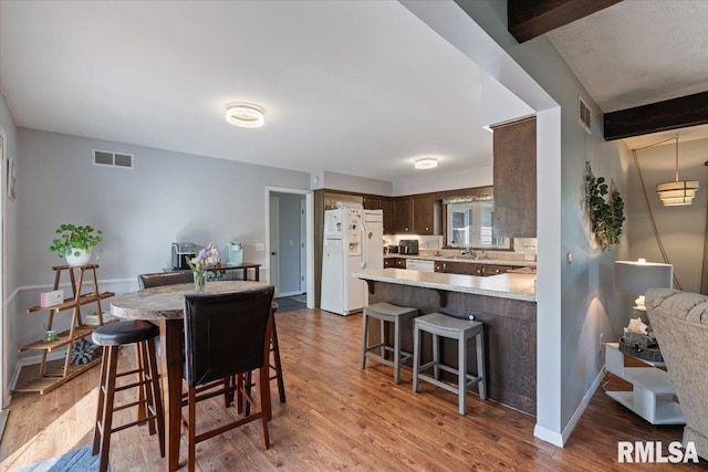 dining area with beam ceiling and wood finished floors