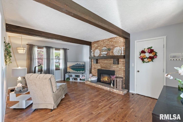 living room with beamed ceiling, wood finished floors, a textured ceiling, and a fireplace