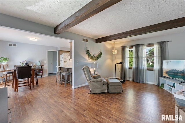 living room featuring a textured ceiling, beam ceiling, wood finished floors, and baseboards