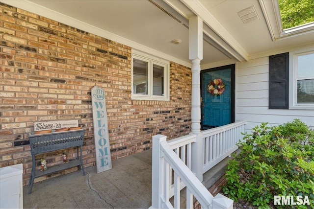 doorway to property with covered porch and brick siding