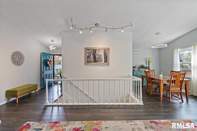 interior space with wood finished floors, lofted ceiling, and a textured ceiling