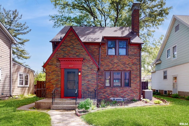 2117 Harrison St, Davenport, IA 52803 - english style home with brick siding, central AC unit, a front lawn, a chimney, and a shingled roof
