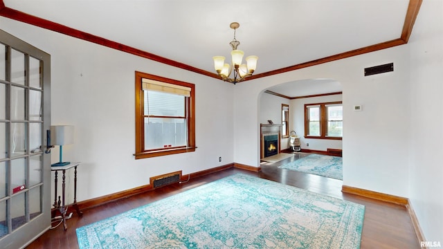 2117 Harrison St, Davenport, IA 52803 - spare room featuring arched walkways, a chandelier, wood finished floors, crown molding, and a fireplace with flush hearth