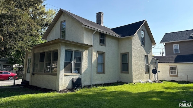 view of property exterior with a chimney, stucco siding, and a yard