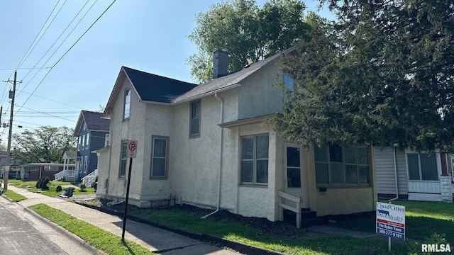 view of side of property with stucco siding and a chimney