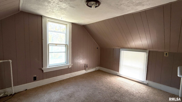 bonus room with vaulted ceiling, carpet flooring, baseboards, and wooden walls