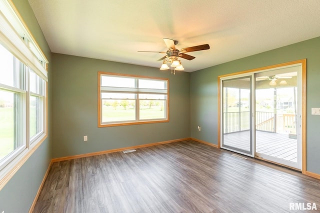 unfurnished room with a ceiling fan, baseboards, wood finished floors, and healthy amount of natural light