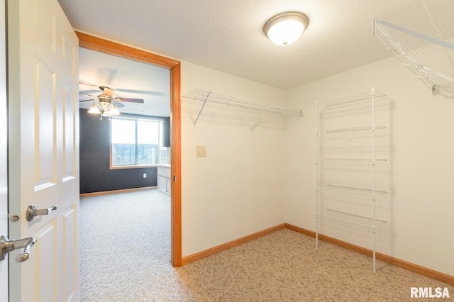spacious closet with light colored carpet and a ceiling fan