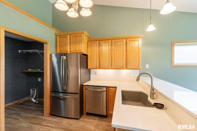 kitchen featuring appliances with stainless steel finishes, a sink, light countertops, light wood-type flooring, and high vaulted ceiling