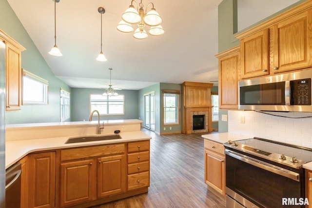 kitchen with appliances with stainless steel finishes, a sink, a chandelier, open floor plan, and lofted ceiling