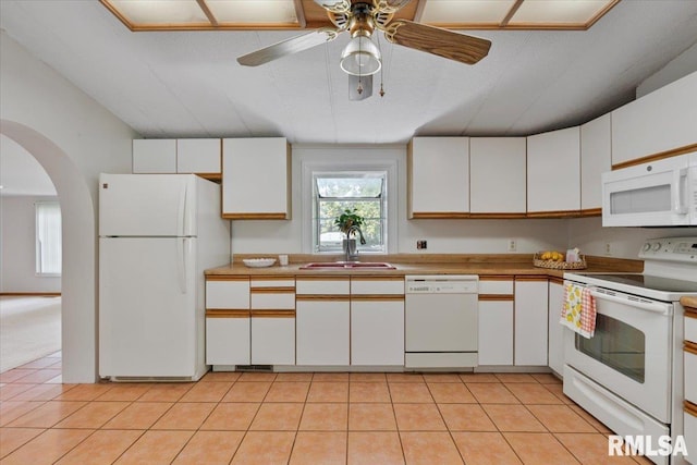 kitchen featuring white appliances, a sink, arched walkways, white cabinetry, and lofted ceiling