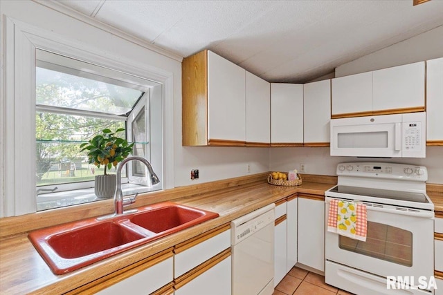 kitchen with white appliances, a sink, light countertops, white cabinets, and vaulted ceiling