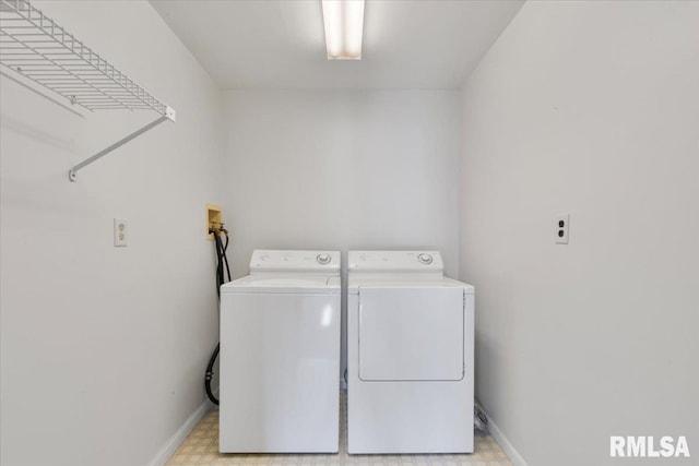 clothes washing area with washing machine and clothes dryer, baseboards, and light floors