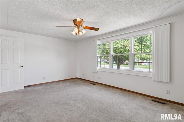 carpeted spare room with a ceiling fan, baseboards, and a textured ceiling