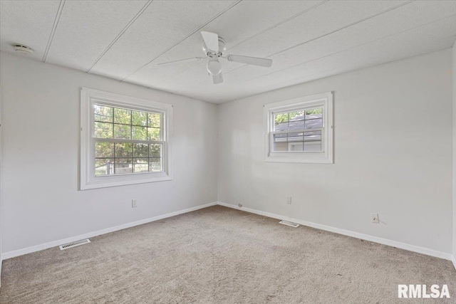 carpeted spare room with plenty of natural light, ceiling fan, and baseboards