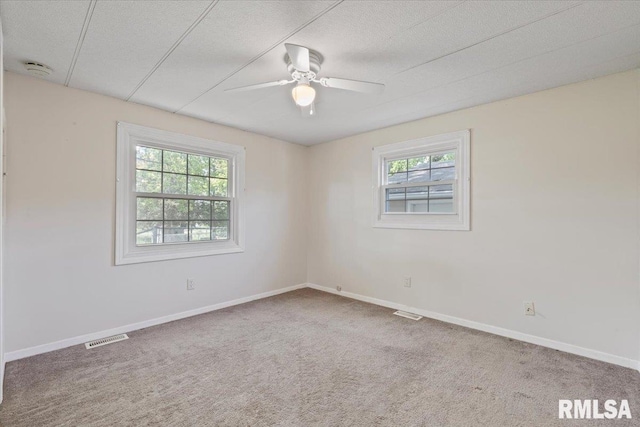 spare room with healthy amount of natural light, a smoke detector, ceiling fan, carpet flooring, and a textured ceiling