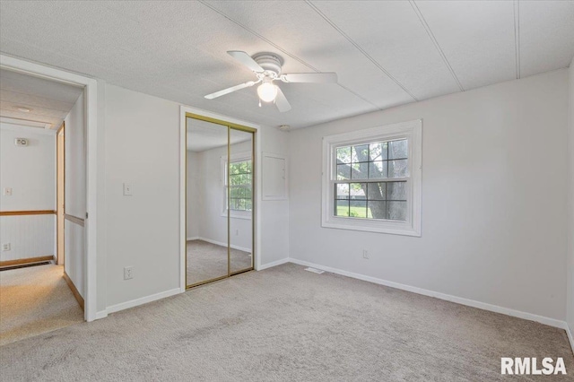 unfurnished bedroom with carpet floors, multiple windows, and a closet