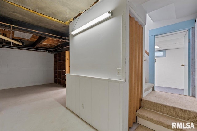 basement featuring stairway and a wainscoted wall