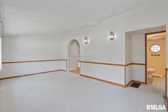 empty room with arched walkways, carpet, baseboards, and ornamental molding