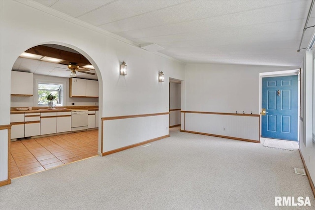 unfurnished room featuring arched walkways, light colored carpet, a ceiling fan, ornamental molding, and a sink