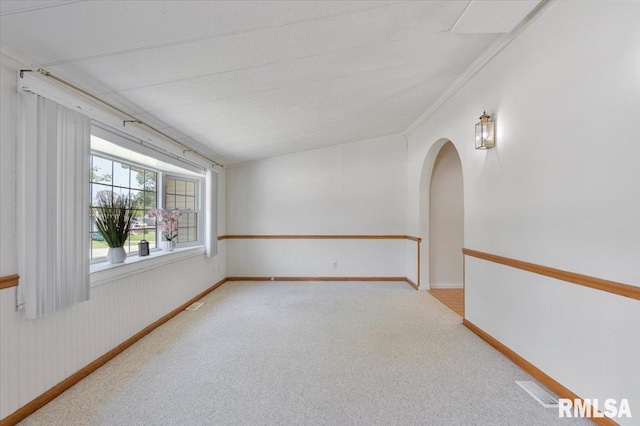 carpeted empty room with arched walkways and baseboards