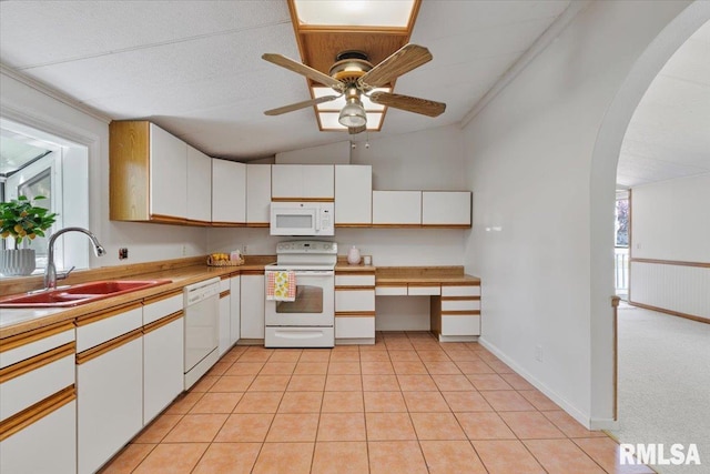 kitchen featuring white appliances, a sink, lofted ceiling, arched walkways, and ceiling fan