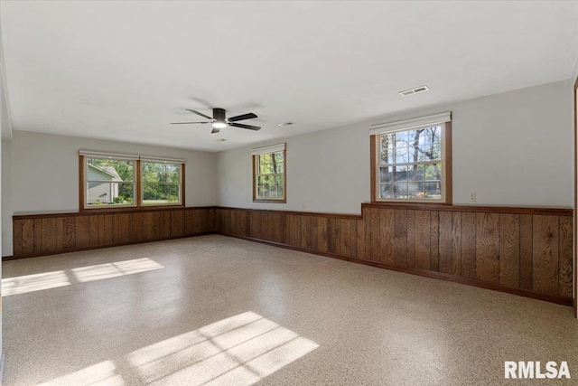 1401 265th St, Sherrard, IL 61281 - empty room with a wainscoted wall, wood walls, and ceiling fan