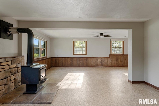 1401 265th St, Sherrard, IL 61281 - spare room featuring a wainscoted wall, a wood stove, wooden walls, and ceiling fan