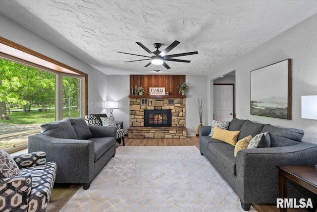 1401 265th St, Sherrard, IL 61281 - living room with light wood-style flooring, a ceiling fan, a stone fireplace, and a textured ceiling