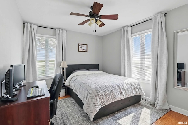 13218 300th St, Donahue, IA 52746 - bedroom featuring wood finished floors, ceiling fan, an office area, and baseboards