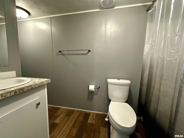 806 Boyd St, Eldorado, IL 62930 - bathroom with wood finished floors, a textured ceiling, toilet, a shower with shower curtain, and vanity