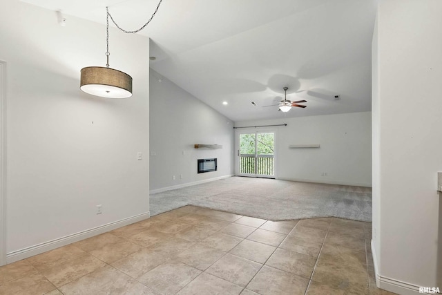 unfurnished living room with lofted ceiling, a ceiling fan, light carpet, a glass covered fireplace, and baseboards