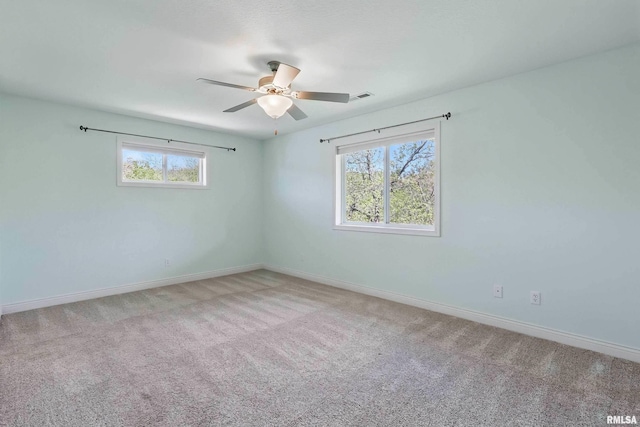carpeted empty room with healthy amount of natural light, ceiling fan, and baseboards
