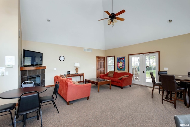 carpeted living area featuring high vaulted ceiling, a fireplace, a ceiling fan, and french doors