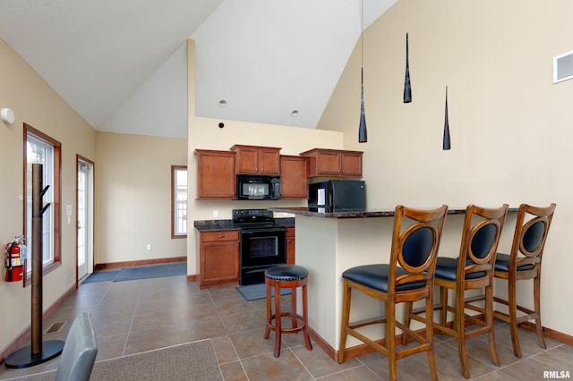 kitchen featuring black appliances, high vaulted ceiling, a breakfast bar, light tile patterned floors, and brown cabinetry