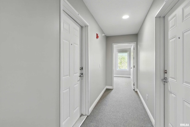 hall with baseboards and light colored carpet