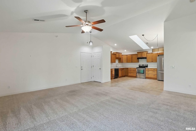unfurnished living room with light colored carpet, ceiling fan, vaulted ceiling, baseboards, and a skylight