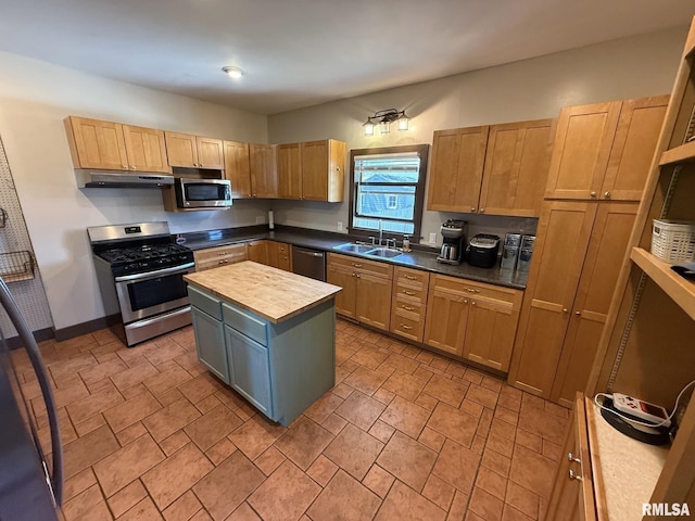 kitchen featuring appliances with stainless steel finishes, a sink, a center island, stone finish flooring, and butcher block counters