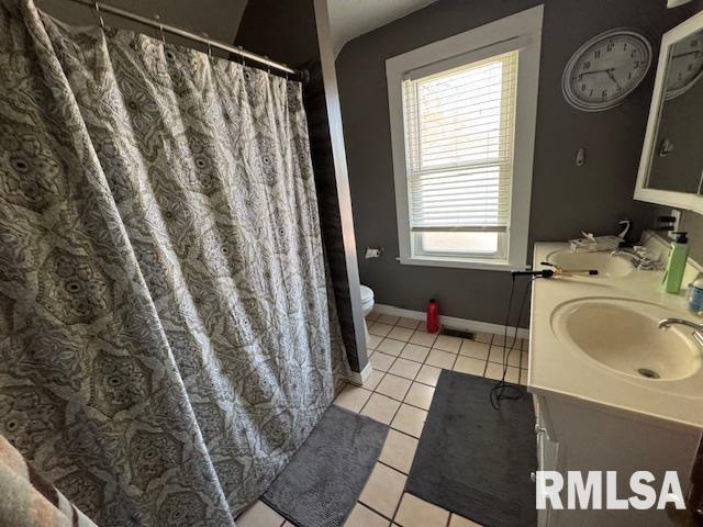 bathroom featuring tile patterned floors, toilet, double vanity, baseboards, and a shower with shower curtain