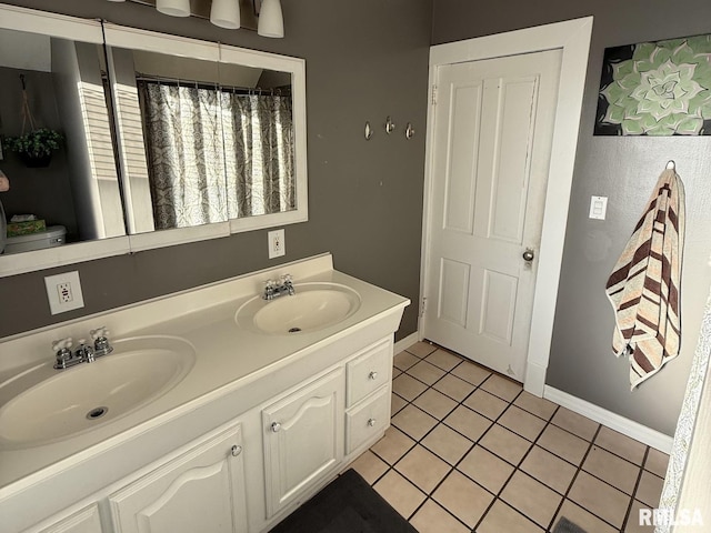 full bath with tile patterned flooring, double vanity, and baseboards