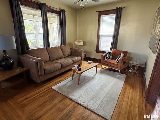 living area featuring wood finished floors, baseboards, and a ceiling fan